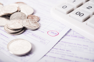 Utility bill with silver coins and calculator