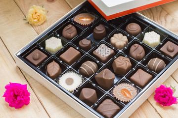 Chocolate candy in the box on wood background.