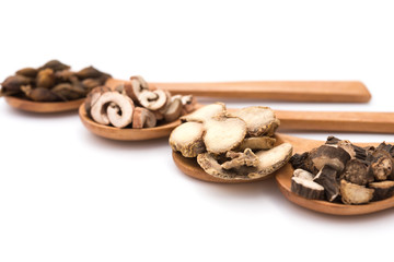 chinese herbs on wooden spoons at a white background