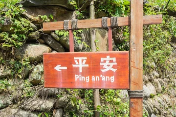 Afwasbaar fotobehang The sign on chinese and english "Ping an'ang" . Pingan one of hte famous village in Longshen, China. © upslim