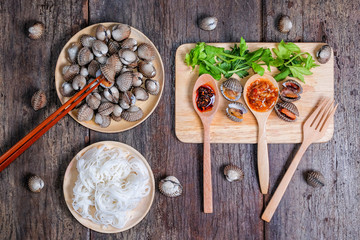 Boiled cockles with rice noodles and tasty seafood sauce on wood table