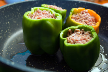 four stuffed with minced pepper in a frying pan, side view