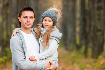 Adorable little girl with father in autumn park outdoors. Happy family together enjoy warm autumn day
