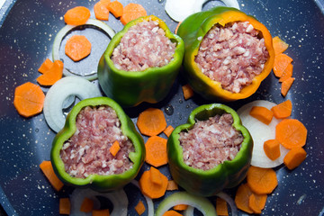 four stuffed with minced pepper with carrot and onion  in a frying pan, top view