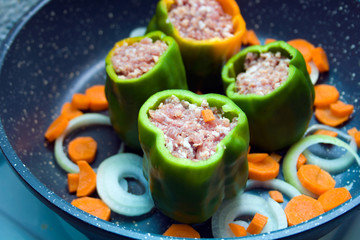 four stuffed with minced pepper with carrot and onion  in a frying pan, top view
