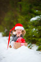 Adorable little girl with Christmas box gift in winter outdoors on Xmas eve