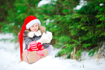 Adorable little girl with Christmas box gift in winter outdoors on Xmas eve