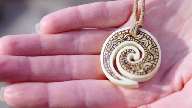 Bone carved pendant in person hand close up 4K