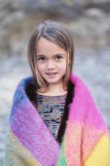 Little girl wrapped in a warm colorful blanket.