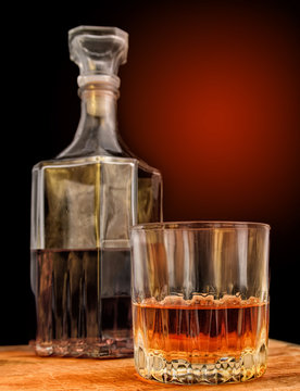 Glass with alcohol against the background of a decanter and a ba