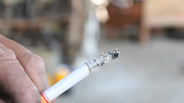 The cigarette with floating smoke in human hand. Health and stop smoking concept