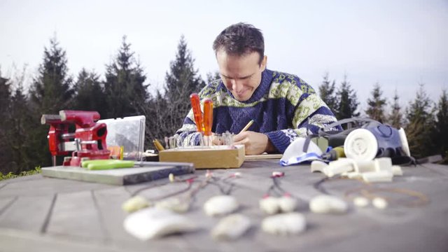 Male person drawing on wooden table outside 4K
