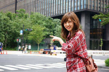 Fototapeta premium Young Asian woman pointing over there while traveling abroad