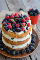 Tasty cake with strawberry, raspberry and blackberry on a wooden table