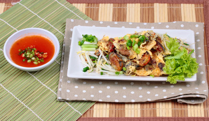 Fried oyster with bean sprouts and shallot as "Hoi Tod" in Thai served with chili sauce. Side View