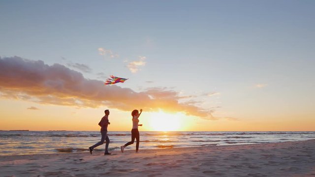 Young couple playing with a kite on the beach at sunset. Steradicam slow motion shot