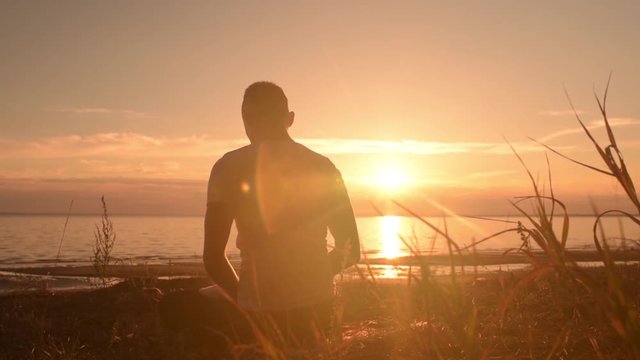 Yoga man sitting on the beach and meditating