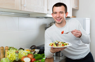 Cheerful  handsome man holding plate with salad