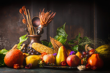 Various fall fruits and vegetables on dark rustic kitchen table at wooden background, side...