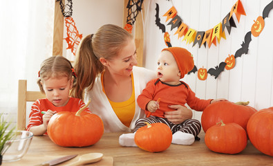 Fototapeta premium Happy family of mother and children prepare for Halloween pumpki
