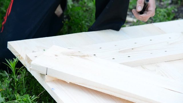 Joiner builds wooden gate from outside