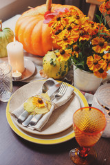 autumn traditional seasonal table setting at home with pumpkins, candles and flowers, selective focus