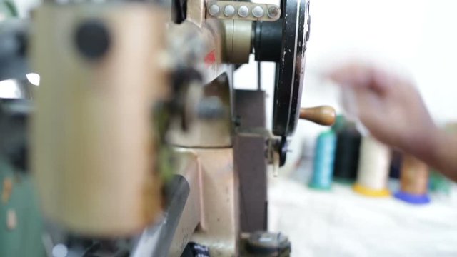 Calzolaio al Lavoro nella sua bottega artigianale. Sistemazione filo macchina da cucire. 