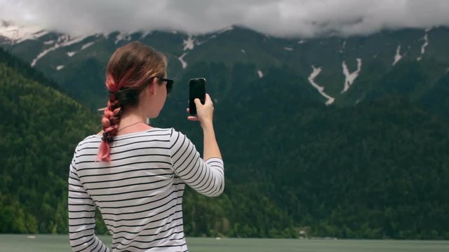 Girl taking photo with smart phone near the mountain lake HD