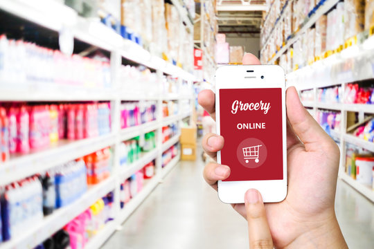 Hand holding smart phone with grocery online on screen