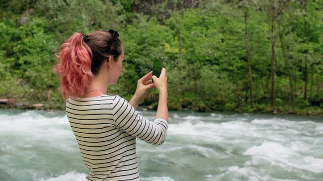 Girl taking photo the river with smart phone HD