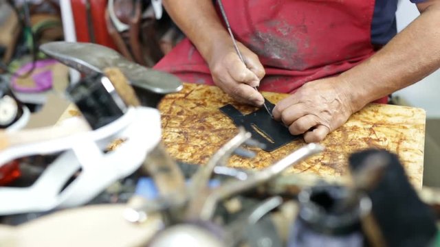 Calzolaio al Lavoro nella sua bottega artigianale. Preparazione per fori su pelle nera. 