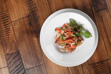 Achichuk - traditional uzbek salad with tomatoes, onions and greens in white plate. wooden background