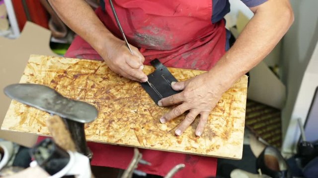 Calzolaio al Lavoro nella sua bottega artigianale. Preparazione per fori su pelle nera. 
