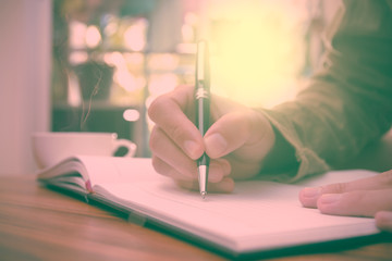 Man hand holding a pen writing on the notebook, Vintage style.