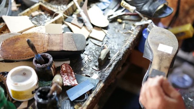 Calzolaio al Lavoro nella sua bottega artigianale. Inchiodatura tacco scarpa nera da donna. 