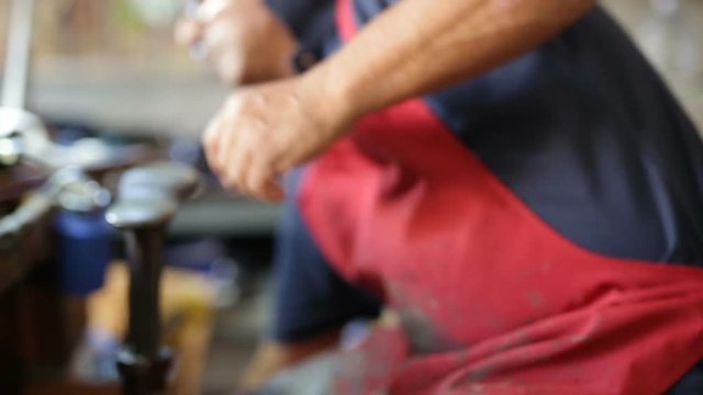Calzolaio al Lavoro nella sua bottega artigianale. Incollatura tacco scarpa alta nera da donna. 