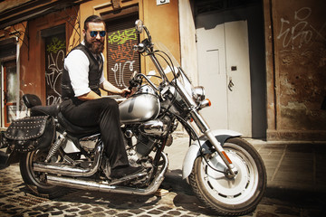 Fototapeta na wymiar Serious Bearded Biker Man Sitting on a Motorcycle