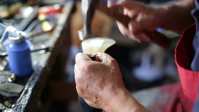 Calzolaio al Lavoro nella sua bottega artigianale. Inchiodatura tacco scarpa alta donna. 