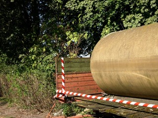 Ladefläche eines alten Anhänger mit Wassertank und Absperrband im Sommer bei Sonnenschein am Barkhauser Weg bei Oerlinghausen und Asemissen bei Bielefeld am Teutoburger in Ostwestfalen-Lippe