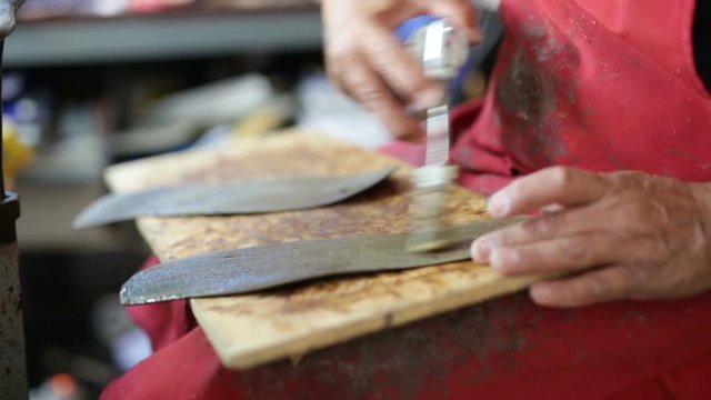 Calzolaio al Lavoro nella sua bottega artigianale. Incollatura suole su tavola di legno poggiata sulle gambe. 