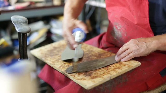 Calzolaio al Lavoro nella sua bottega artigianale. Incollatura suole. 