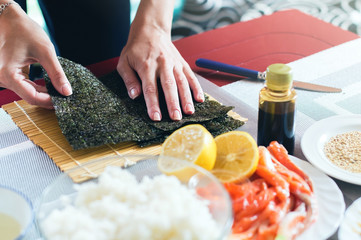 Preparing nori seaweed while making sushi on the home kitchen table © berezko