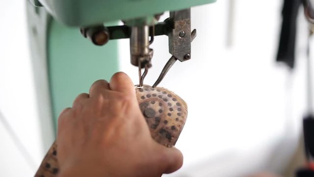 Calzolaio al Lavoro nella sua bottega artigianale. Cucitura di una suola di scarpa uomo. 