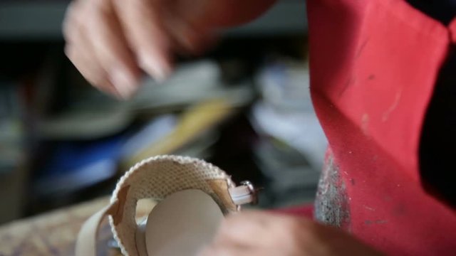 Calzolaio al Lavoro nella sua bottega artigianale. Ritaglio suola scarpa da donna. 