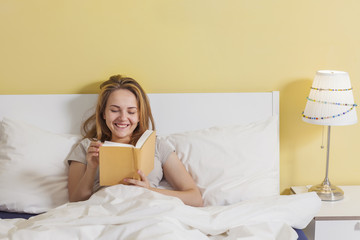 Obraz na płótnie Canvas Teenage girl reading a book in bed
