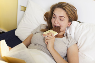 Teen girl in bed eating chocolate