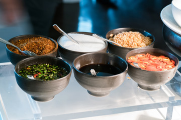 Thai seasoning container include cayenne pepper, sugar, fish sauce and chilies in vinegar.
