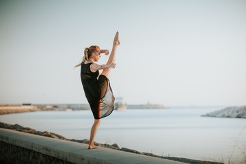 Fototapeta na wymiar Dancer with one leg up, performing dance at seashore.