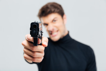 Closeup of angry young man pointing with gun on you