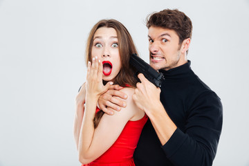 Mad criminal man threatening to scared young woman with gun